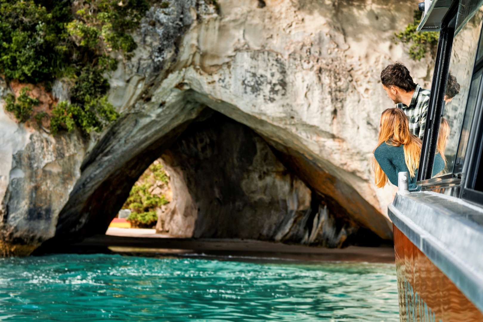 Tour boat cruising along Cathedral Cove’s rocky coastline
